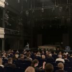 Ogólna sala teatralna, widzowe na widowni, jeszcze prawie pusta scena z rekwizytami, zgaszone reflektory na górze